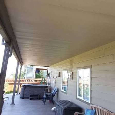 A close up of a gutter on a roof with a house in the background.