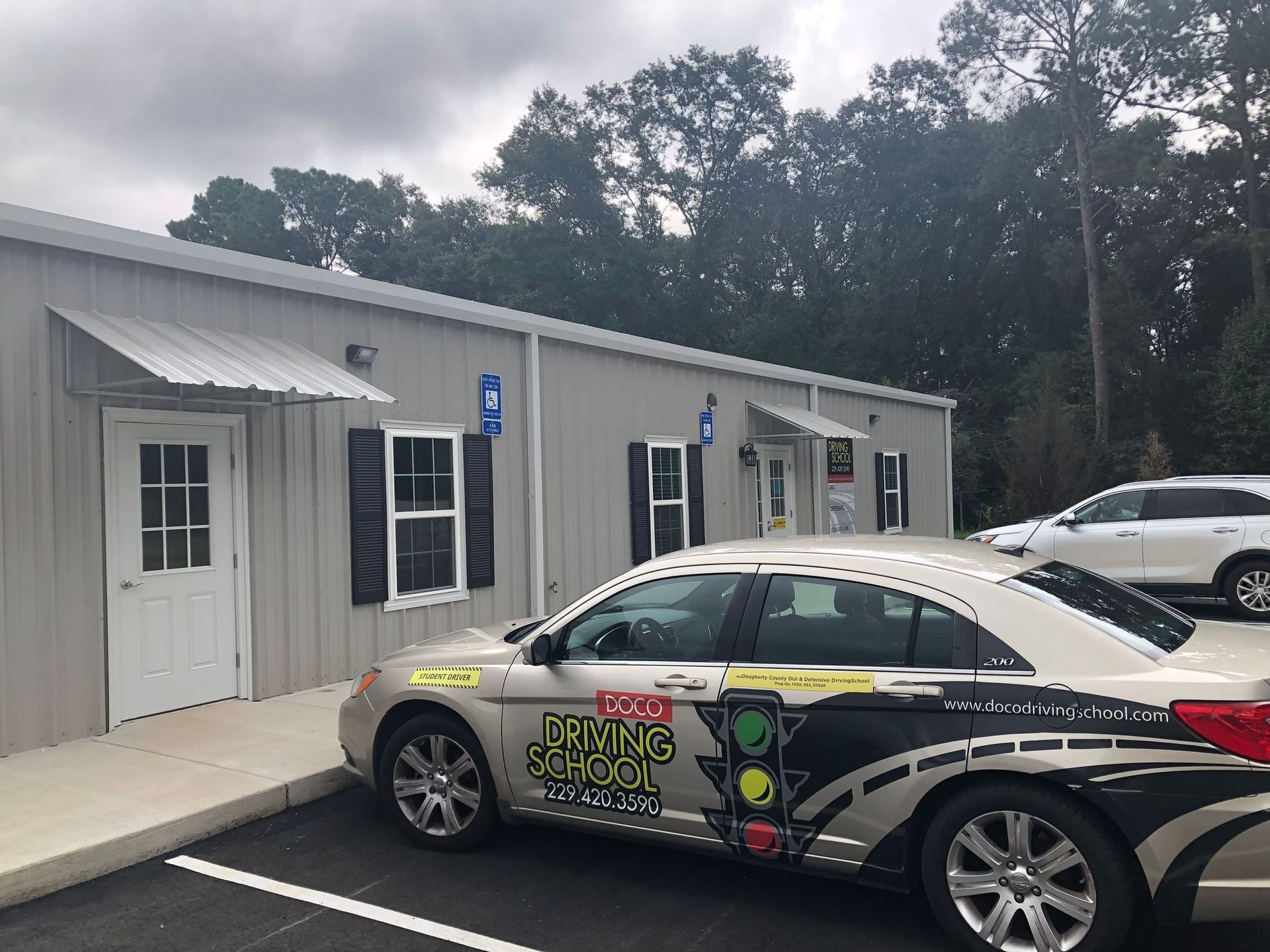 A car is parked in front of a building that says driving school