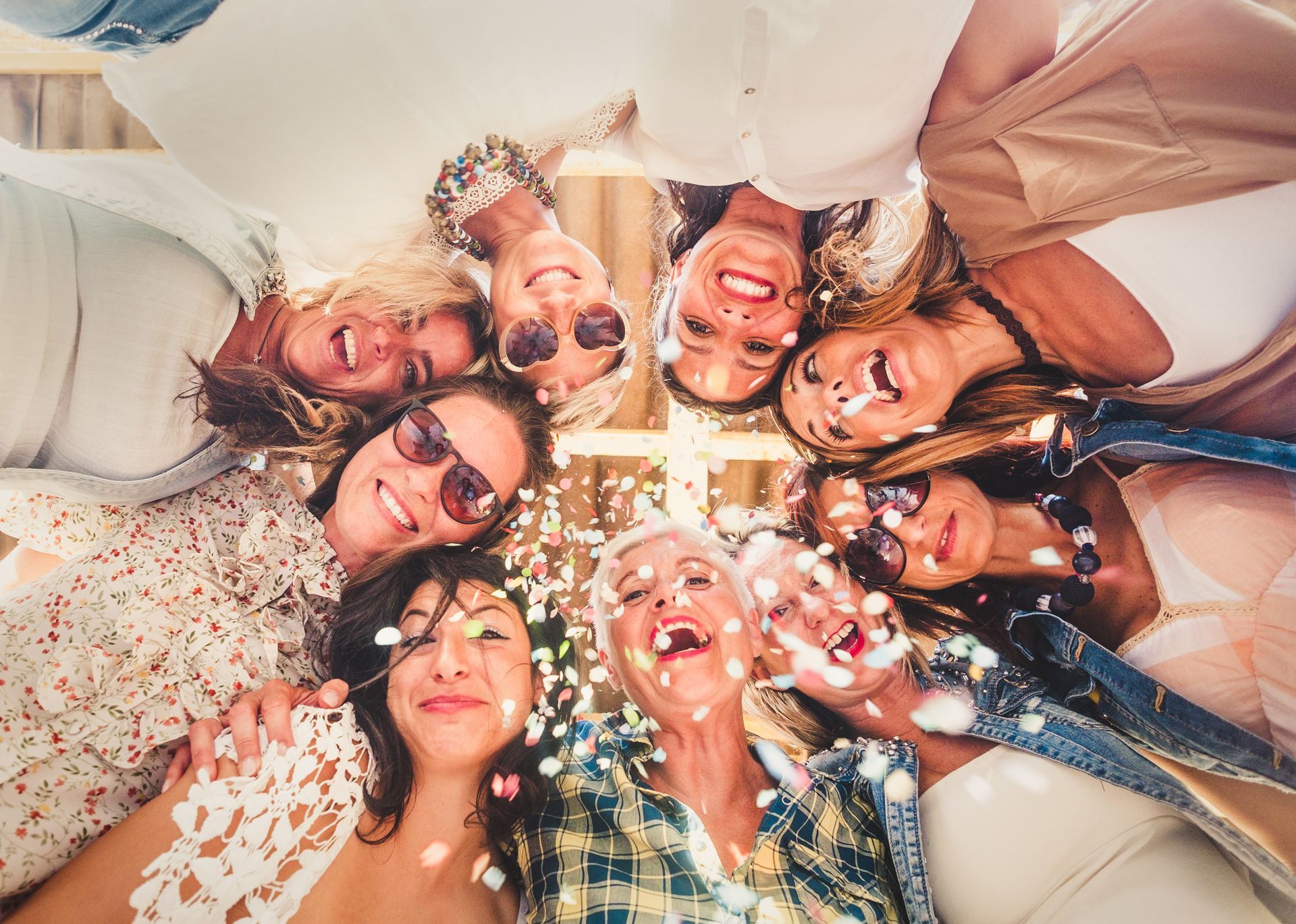 A group of women are standing in a circle with confetti on their faces