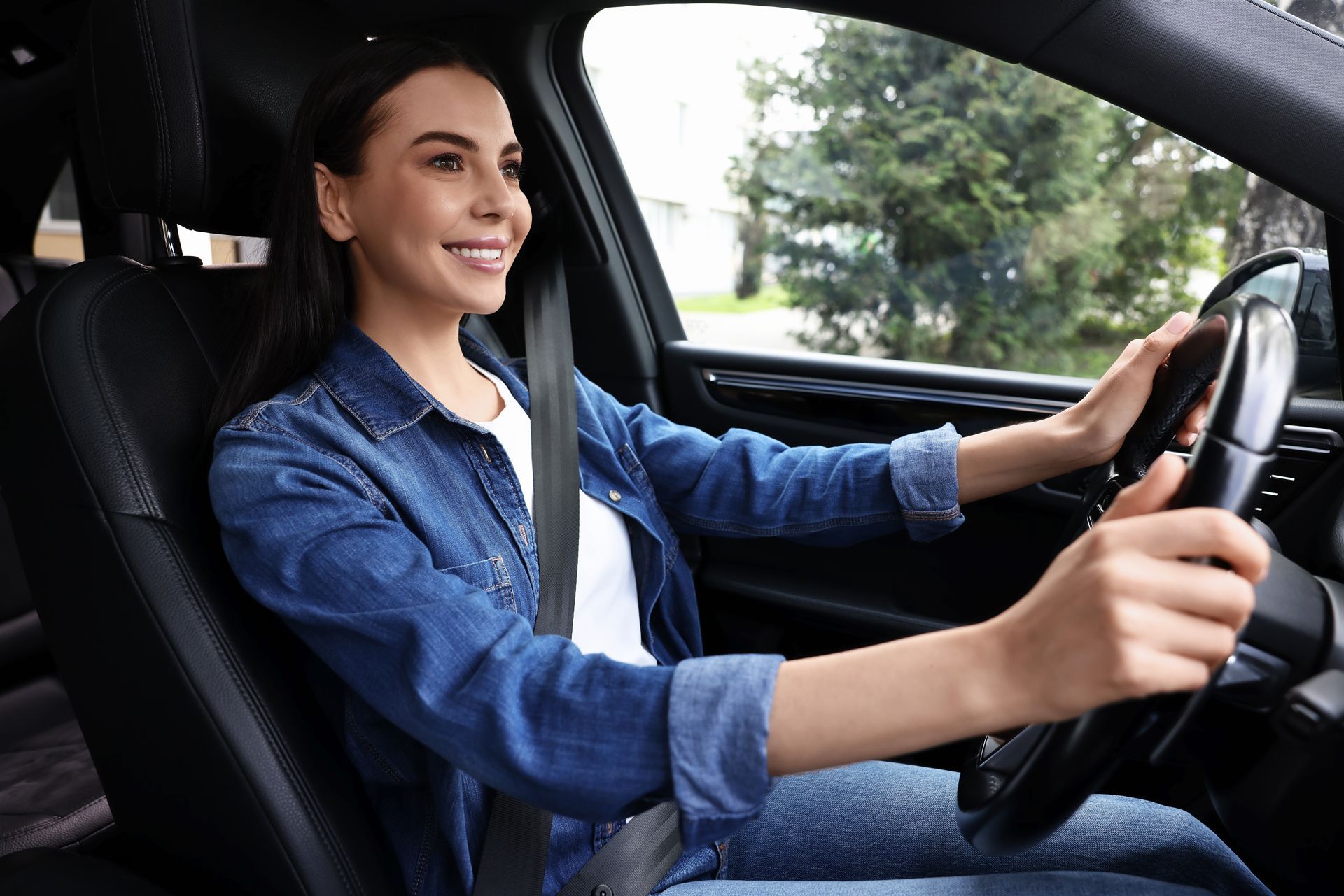 A woman is sitting in the driver 's seat of a car