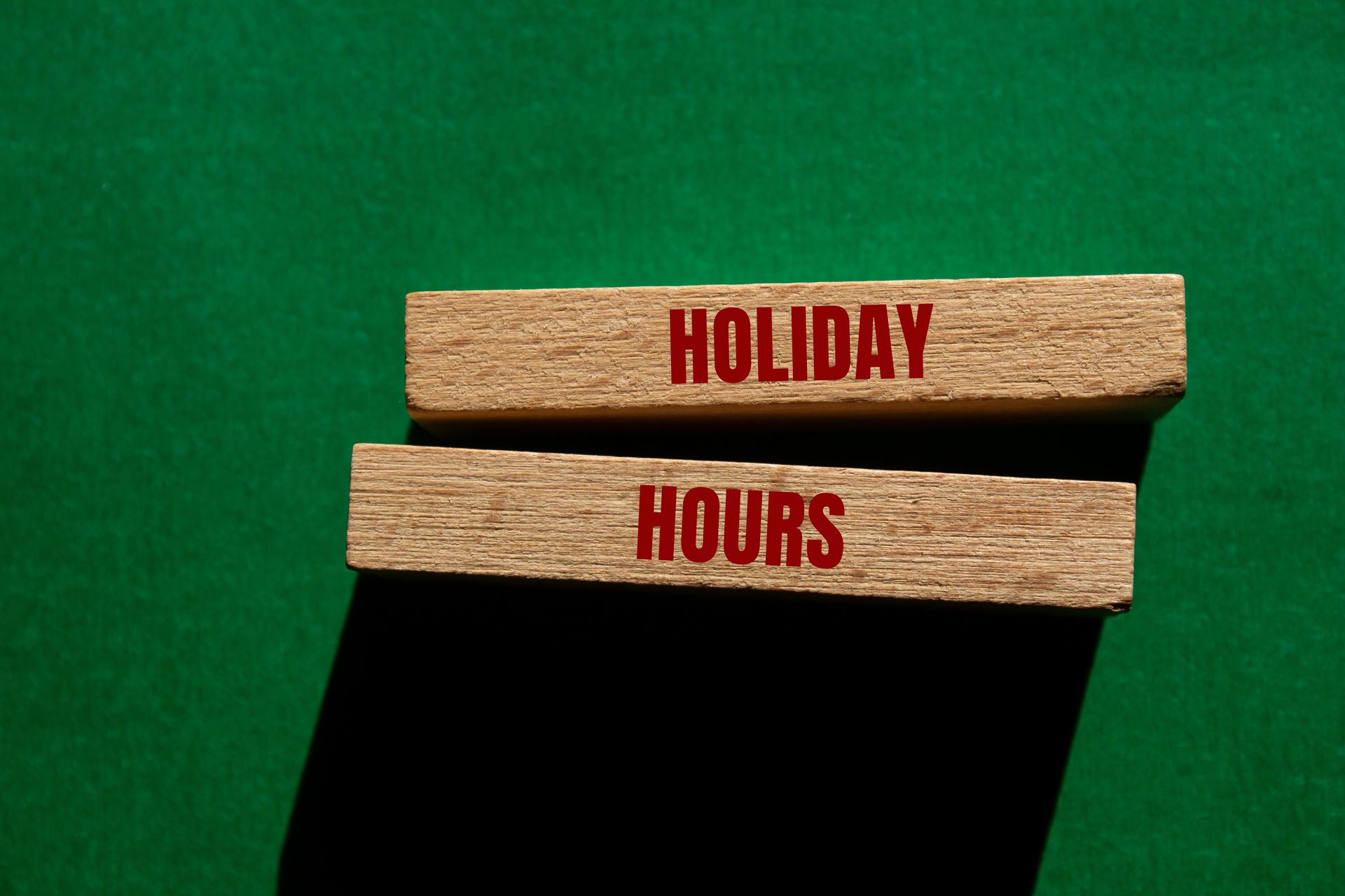 Two wooden blocks with the words holiday hours written on them