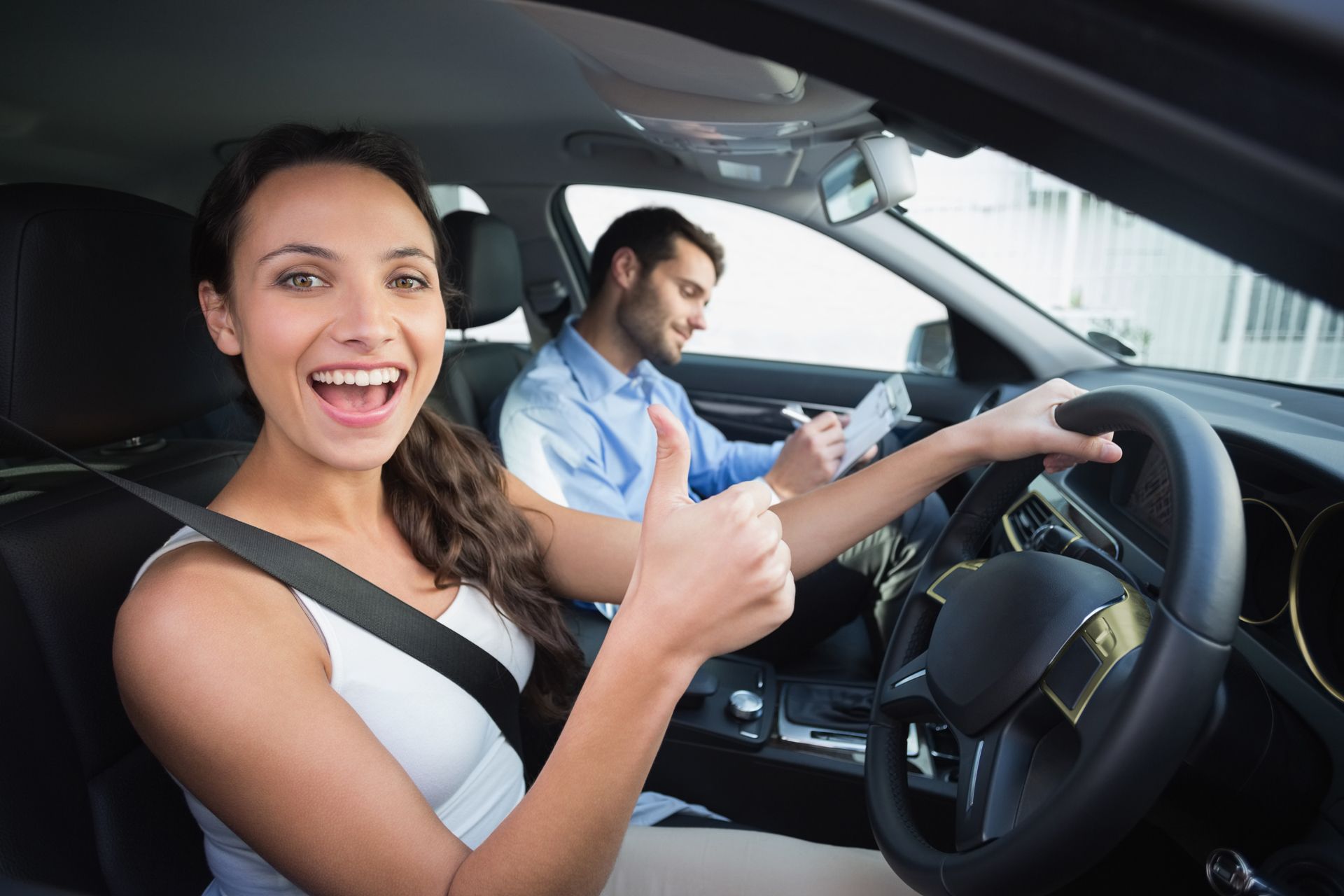 A woman is giving a thumbs up while sitting in a car next to a man