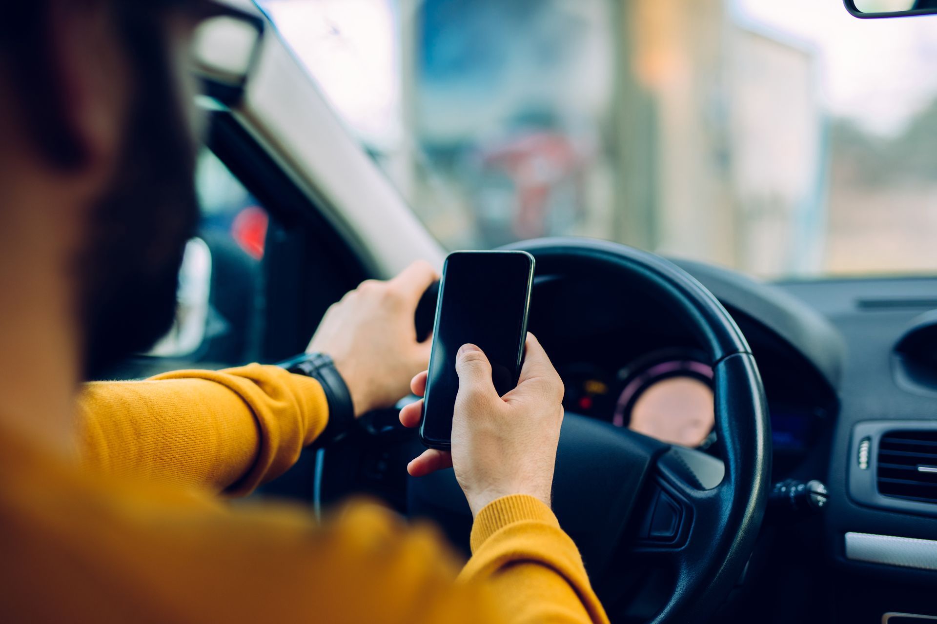 A man is using a cell phone while driving a car