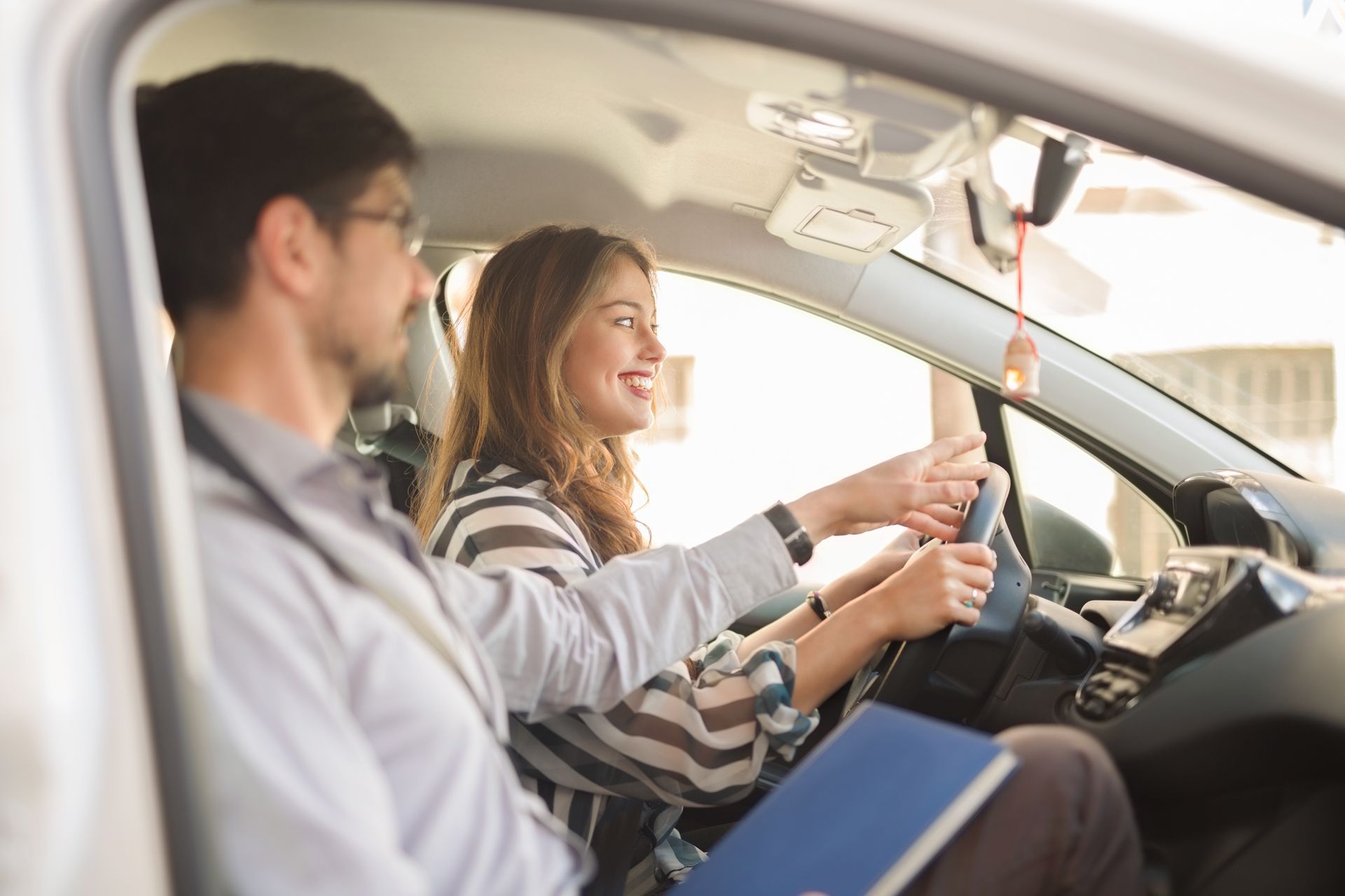 A man is teaching a woman how to drive a car