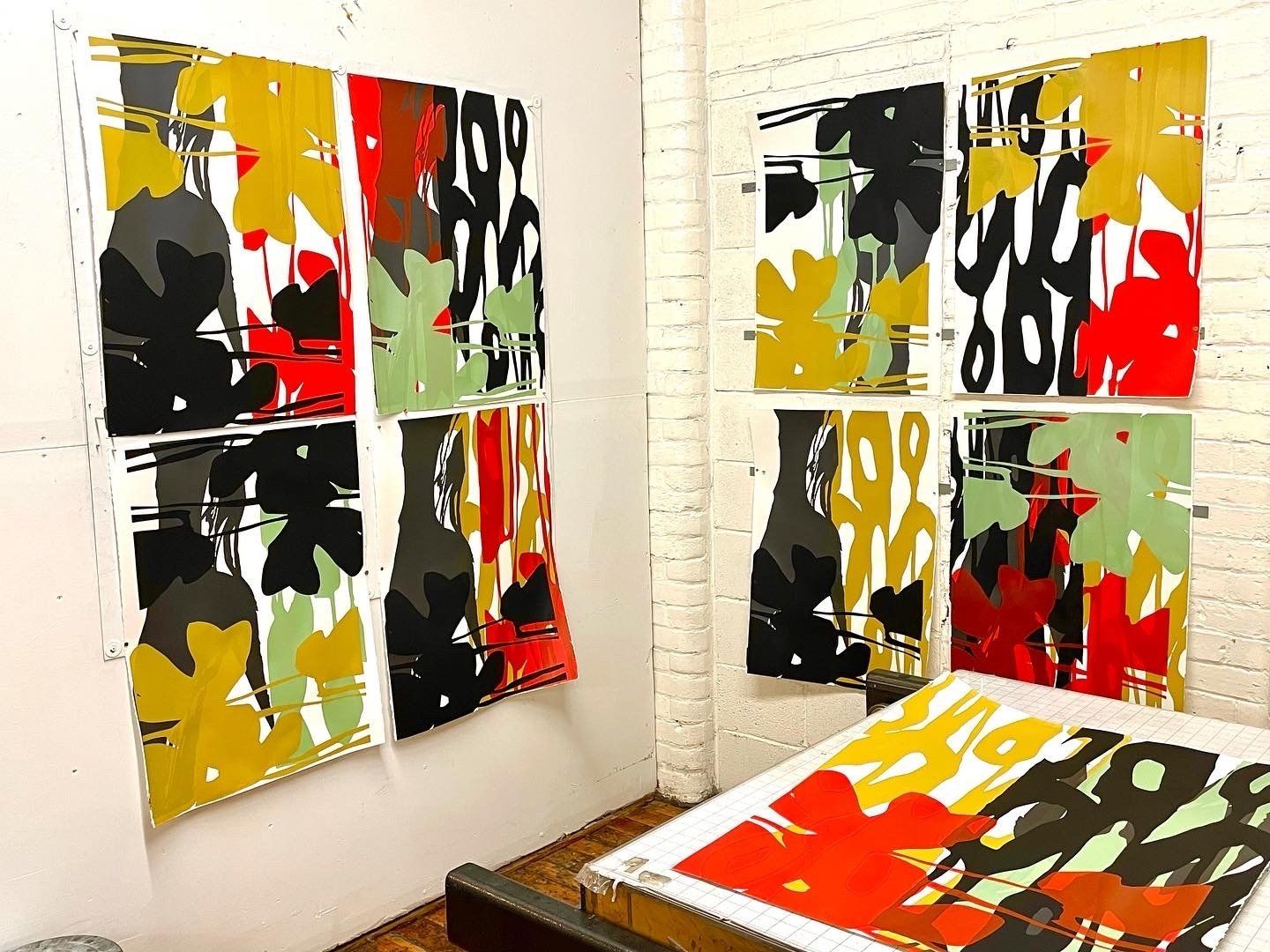 A bunch of paintings are hanging on a wall and one of them has the number 99 on it