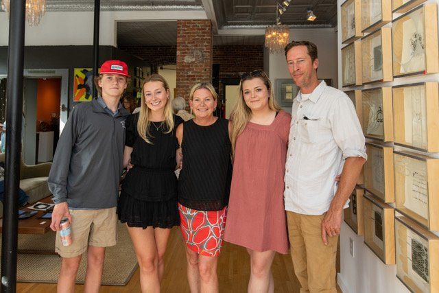 A family posing for a picture in front of a wall of pictures