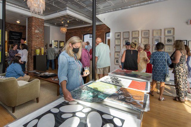 A woman wearing a mask is looking at a painting in an art gallery