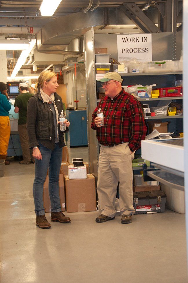 A man and a woman are standing in front of a sign that says work in process