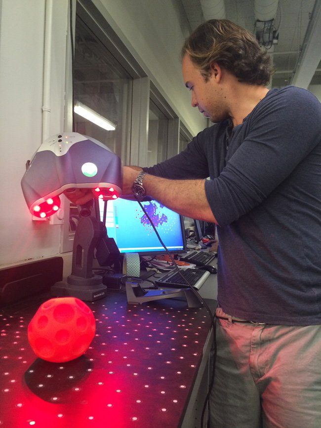 A man is using a machine to scan a red ball