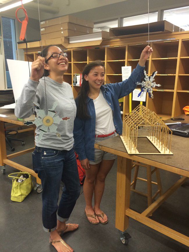 Two girls are standing next to a table with a model on it