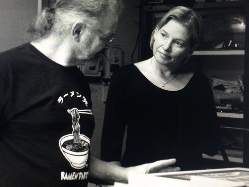 A man wearing a ramen shirt talks to a woman