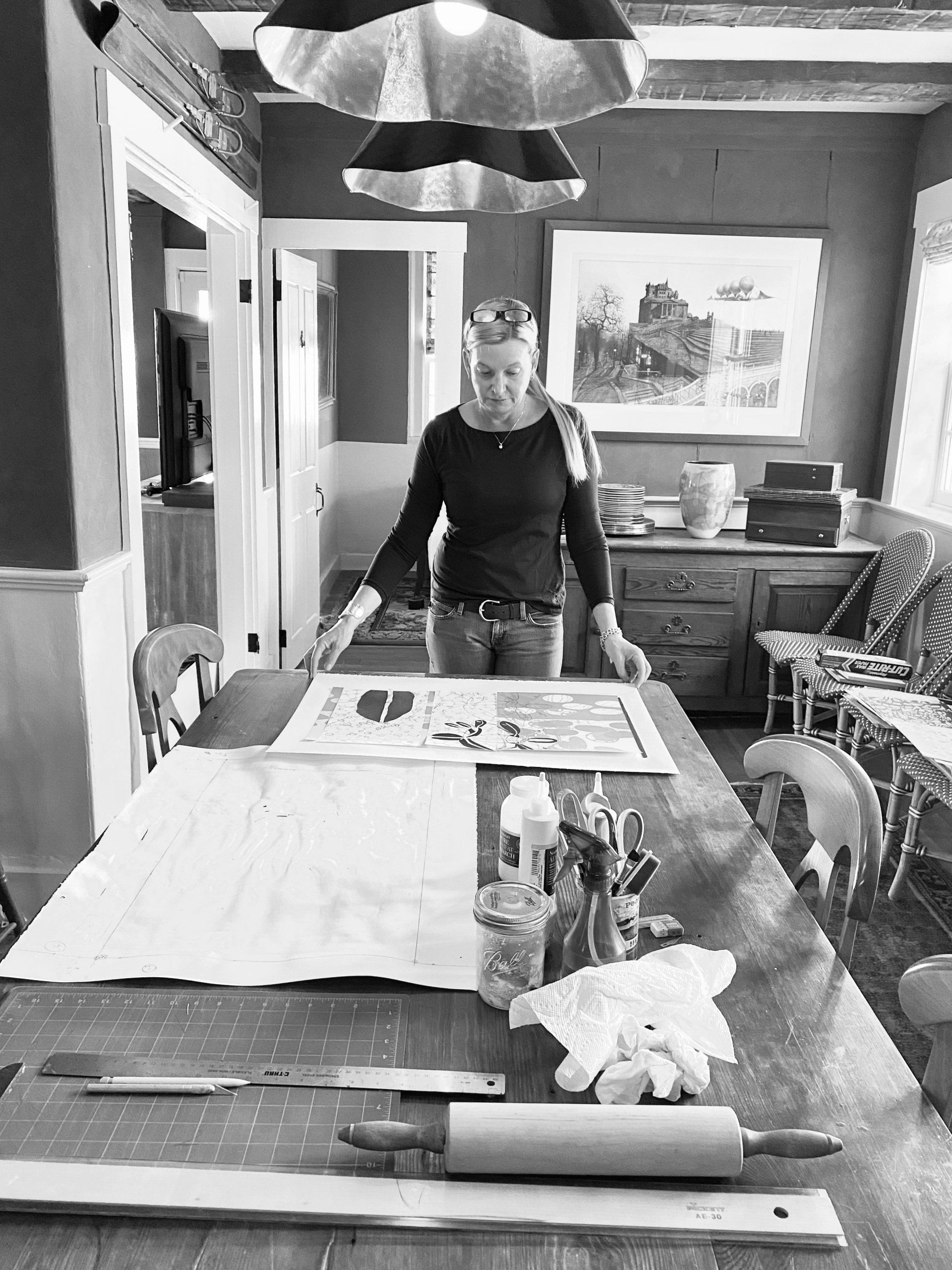 A woman is standing at a table in a black and white photo.