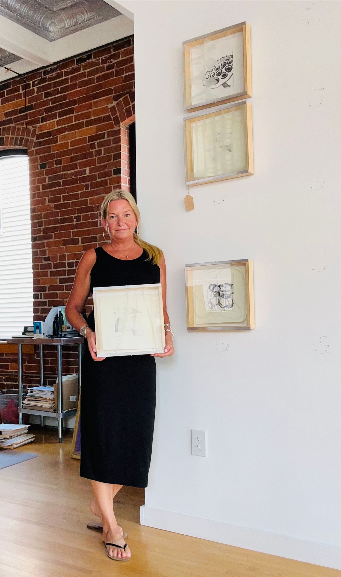 A woman in a black dress is holding a framed picture