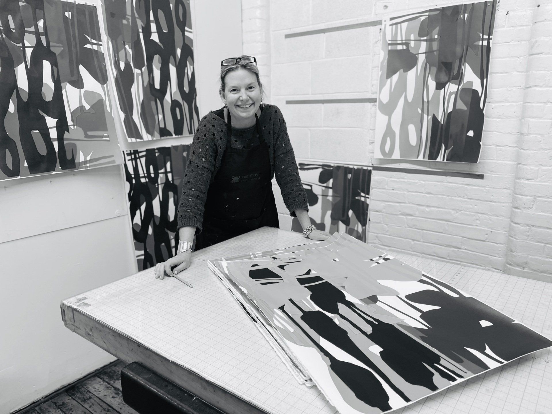 A woman is standing in front of a large painting on a table.