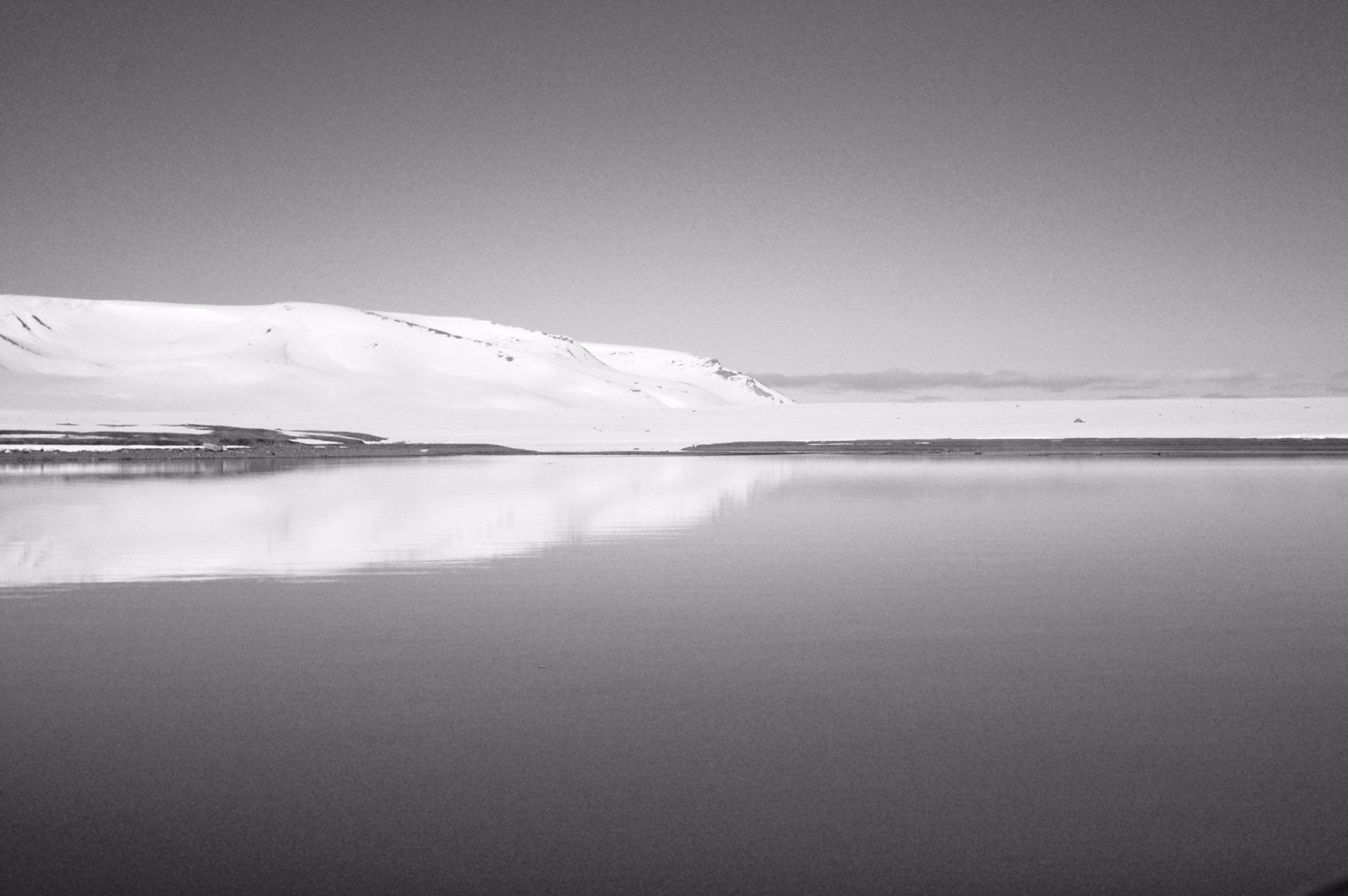 A black and white photo of a lake with mountains in the background.