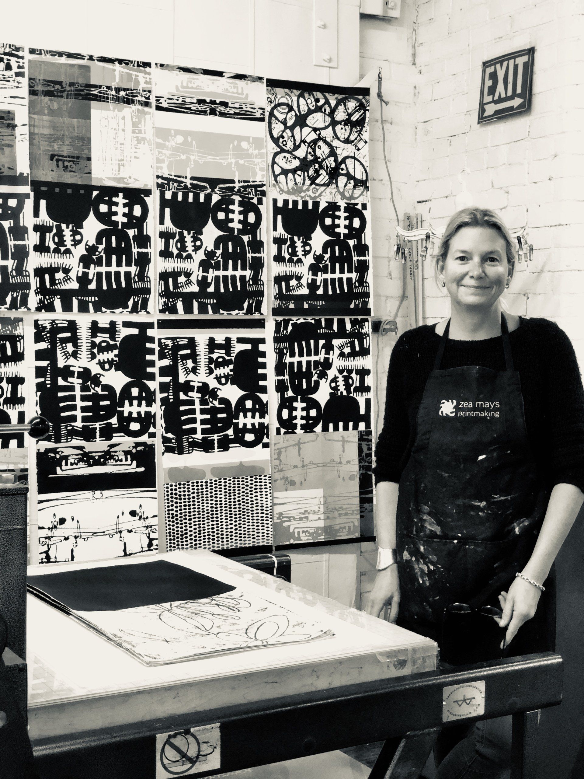 A woman in an apron is standing in front of an exit sign