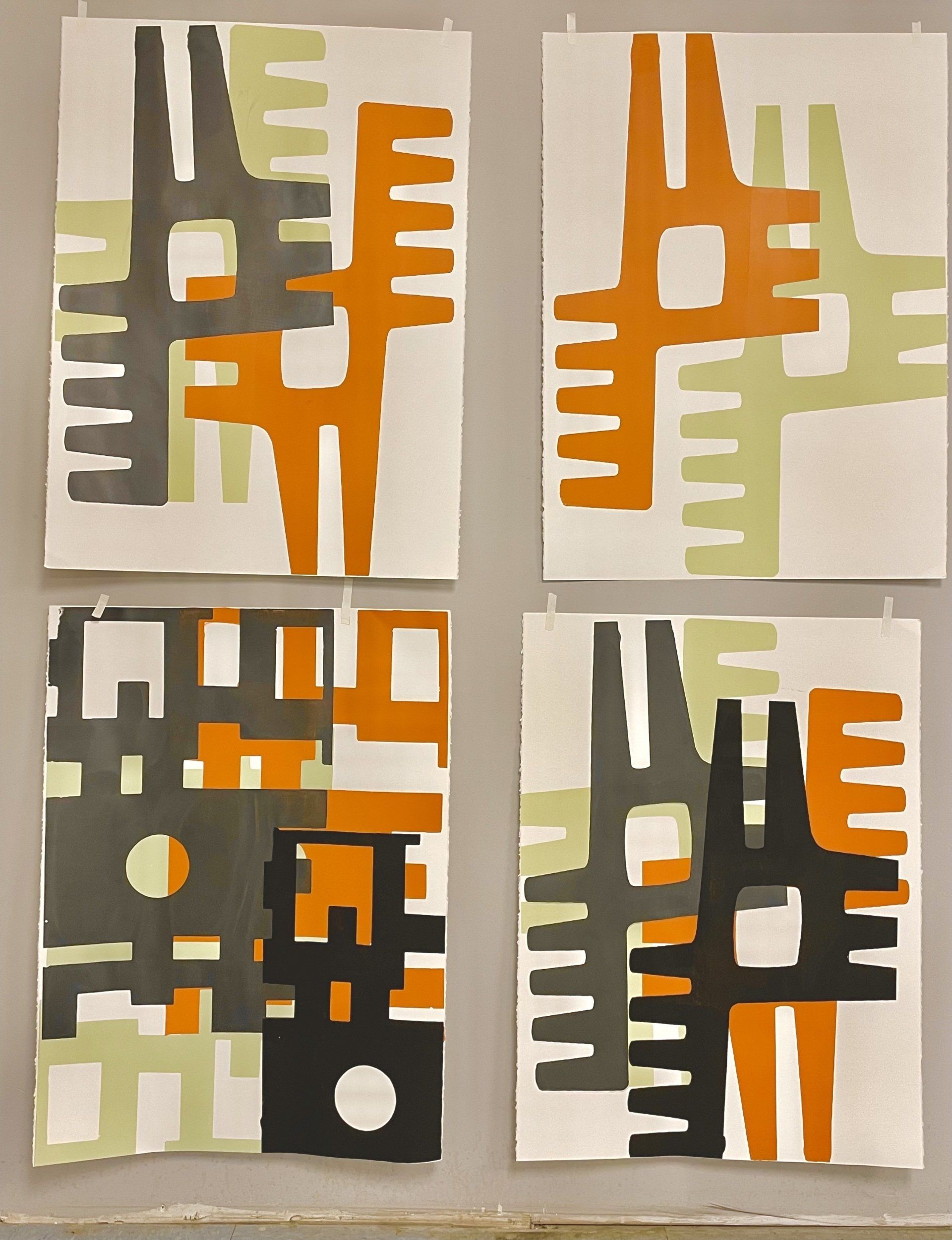 Four paintings are hanging on a wall one of which has the letter e on it