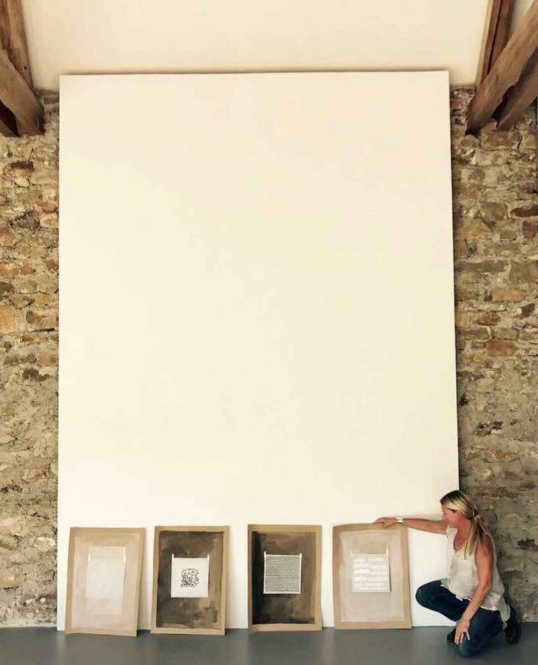 A woman is kneeling in front of a large white wall