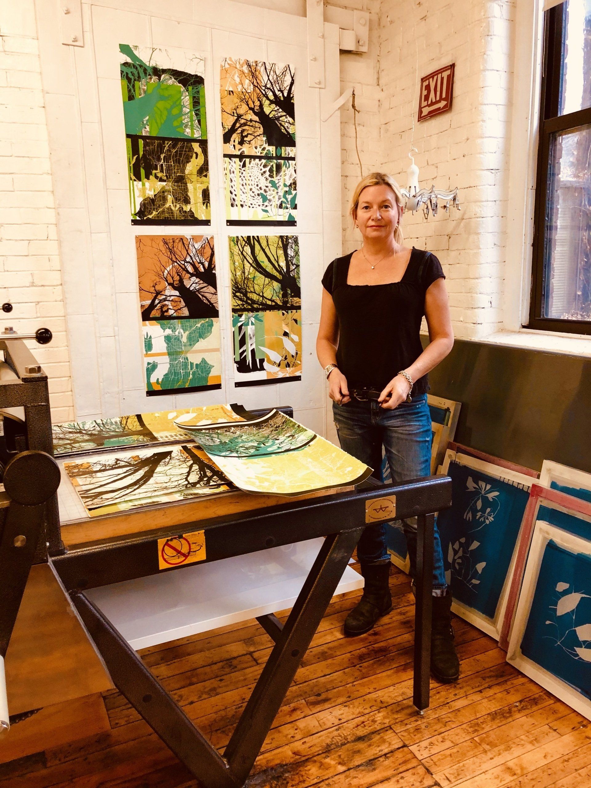 A woman standing in front of a table with a red exit sign on the wall behind her