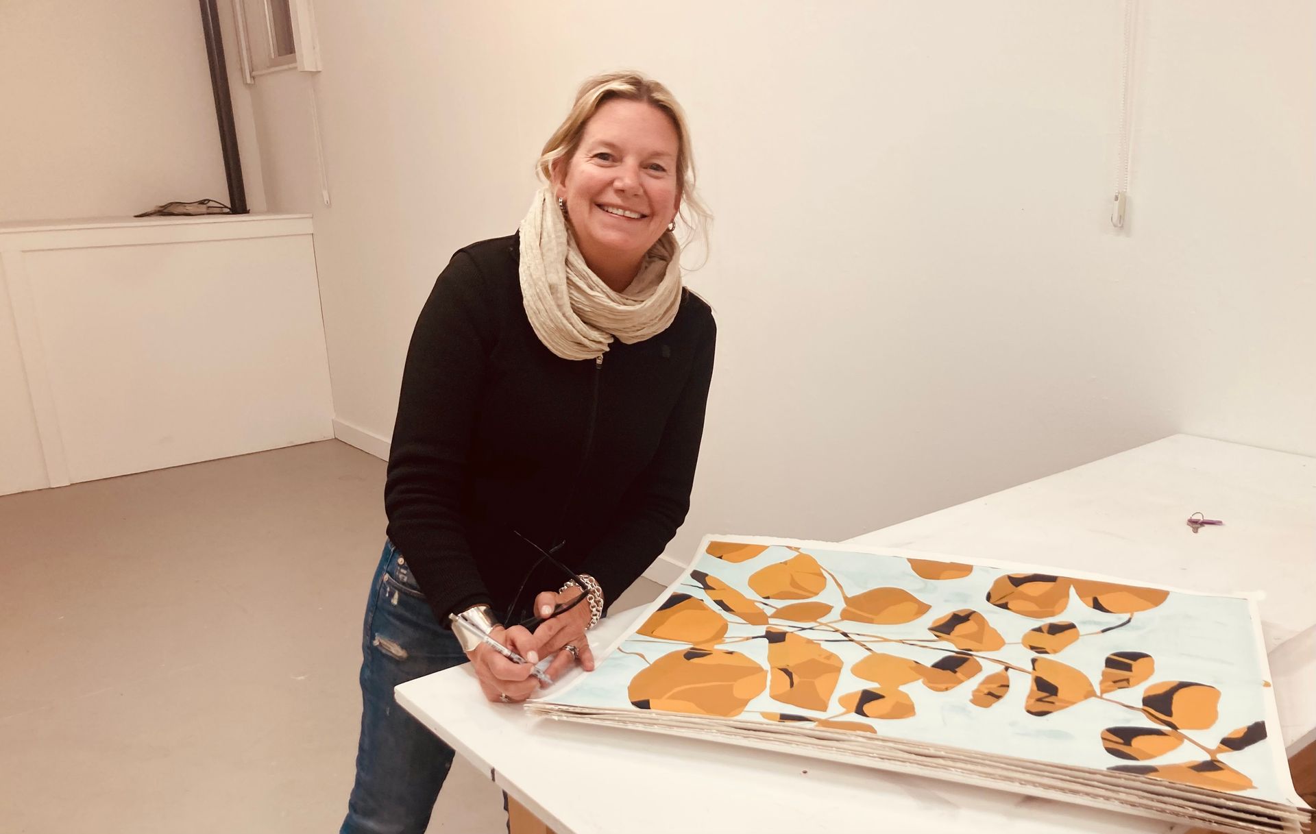 A woman is sitting at a table with a painting on it