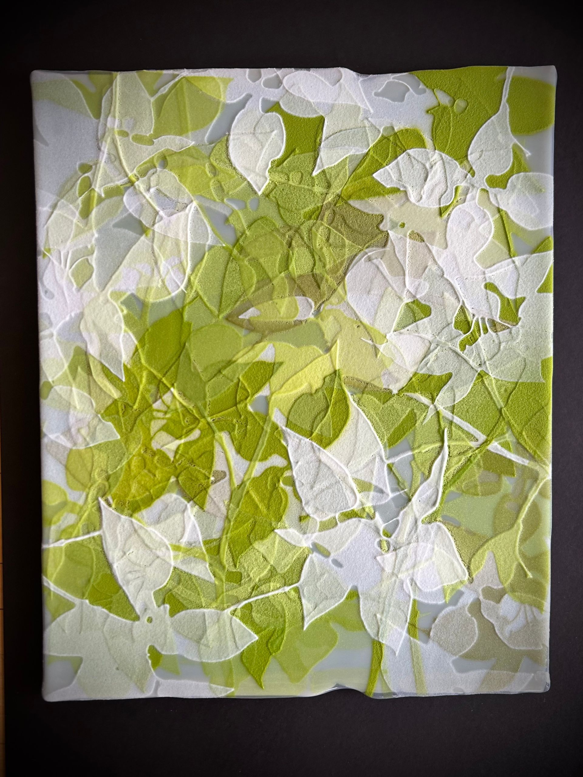 A painting of green and white leaves on a black background