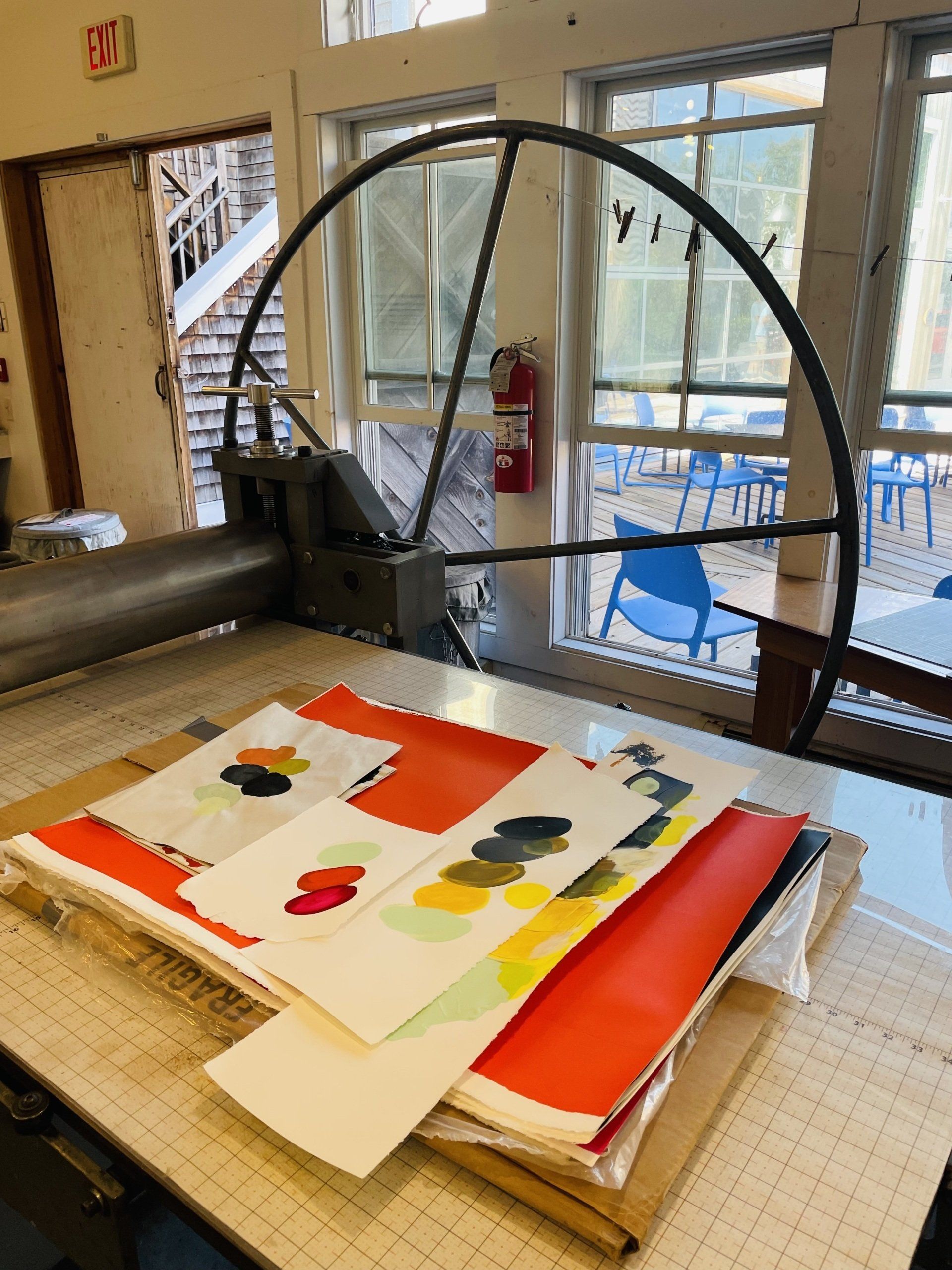 A red fire extinguisher sits on a table in front of an exit sign