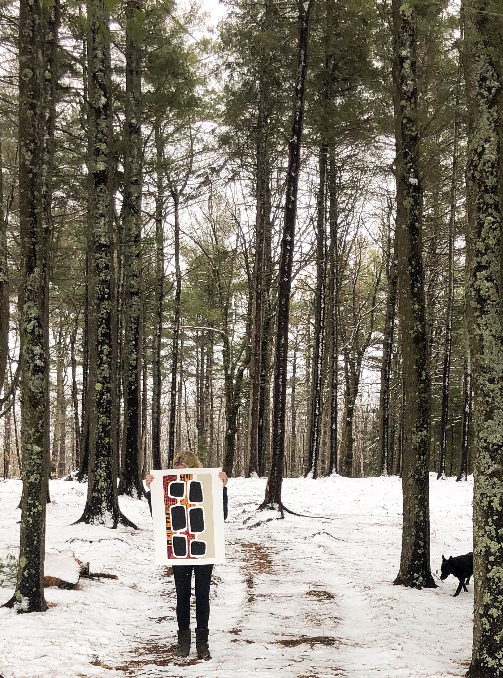 A person holding a piece of art in the middle of a snowy forest