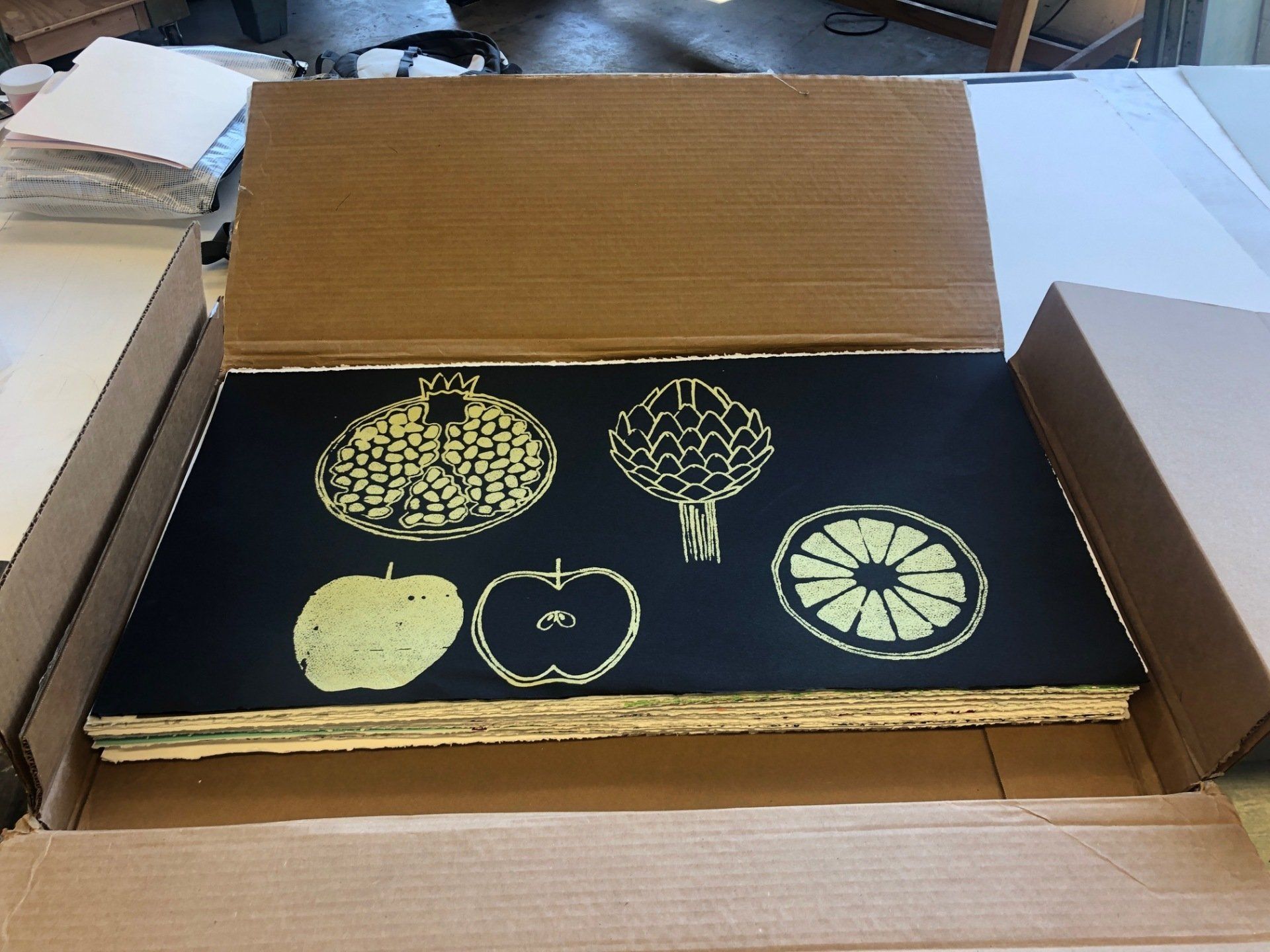 A cardboard box with a black item with yellow images of fruit on it