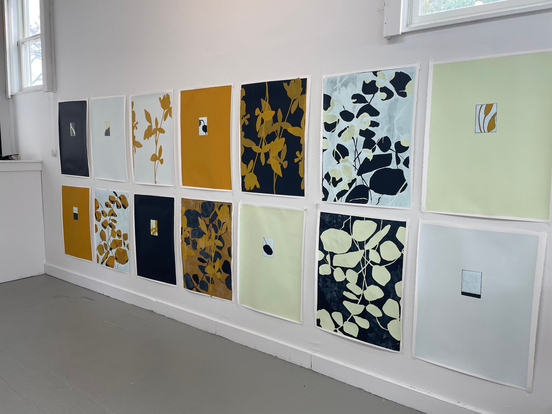 A row of paintings on a wall one of which has the letter p on it