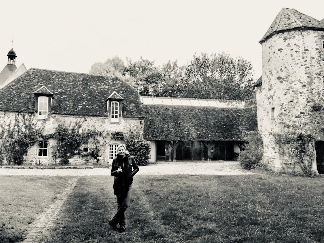 A black and white photo of a man standing in front of a large stone building