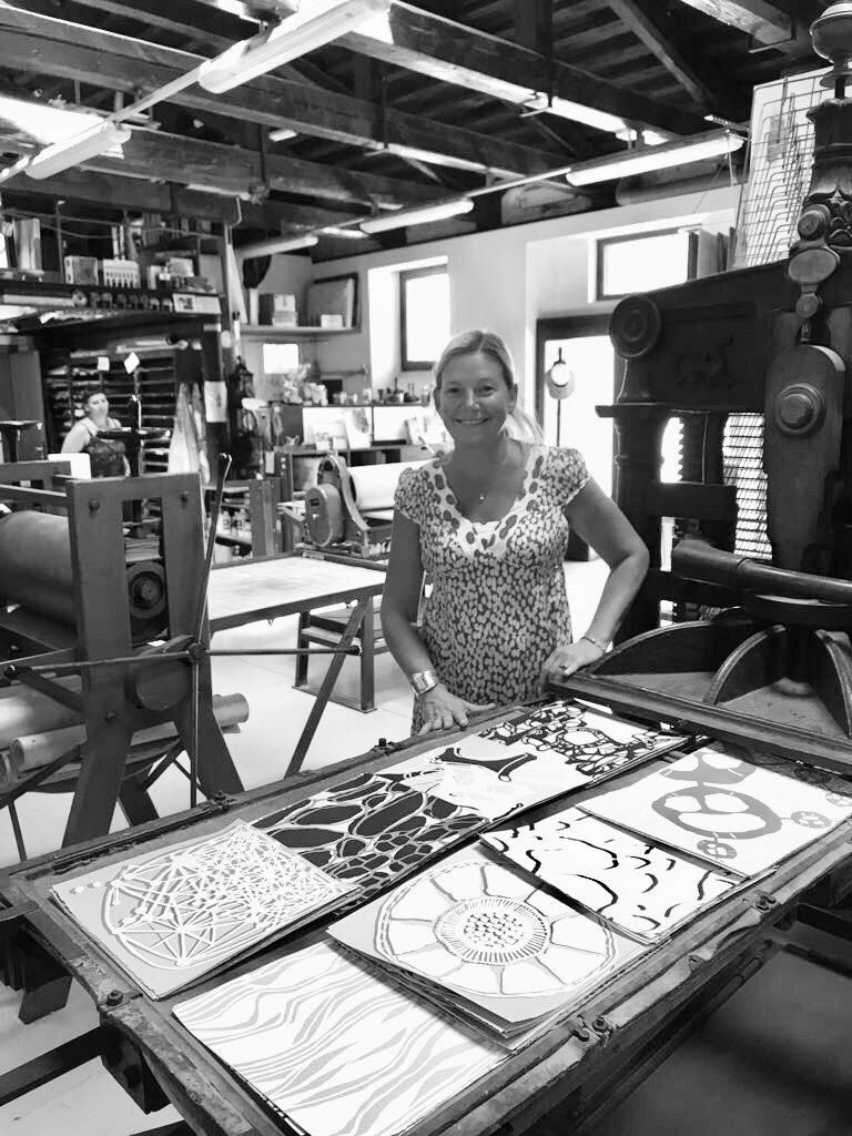 A woman is standing in front of a table with papers on it in a black and white photo.