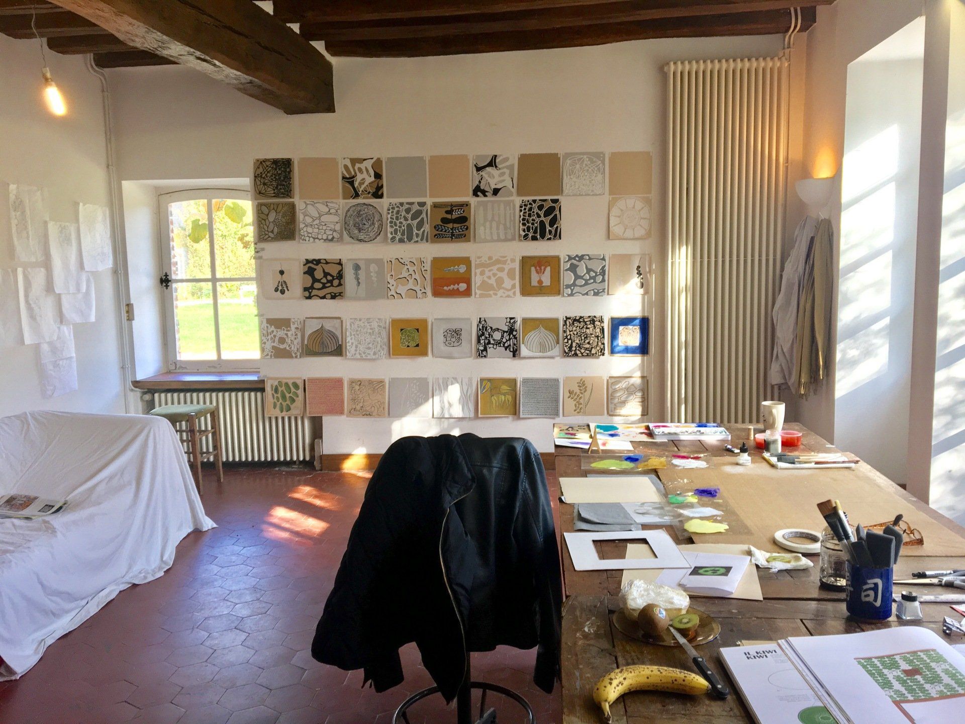 An artist 's studio with paintings on the wall and a banana on the table