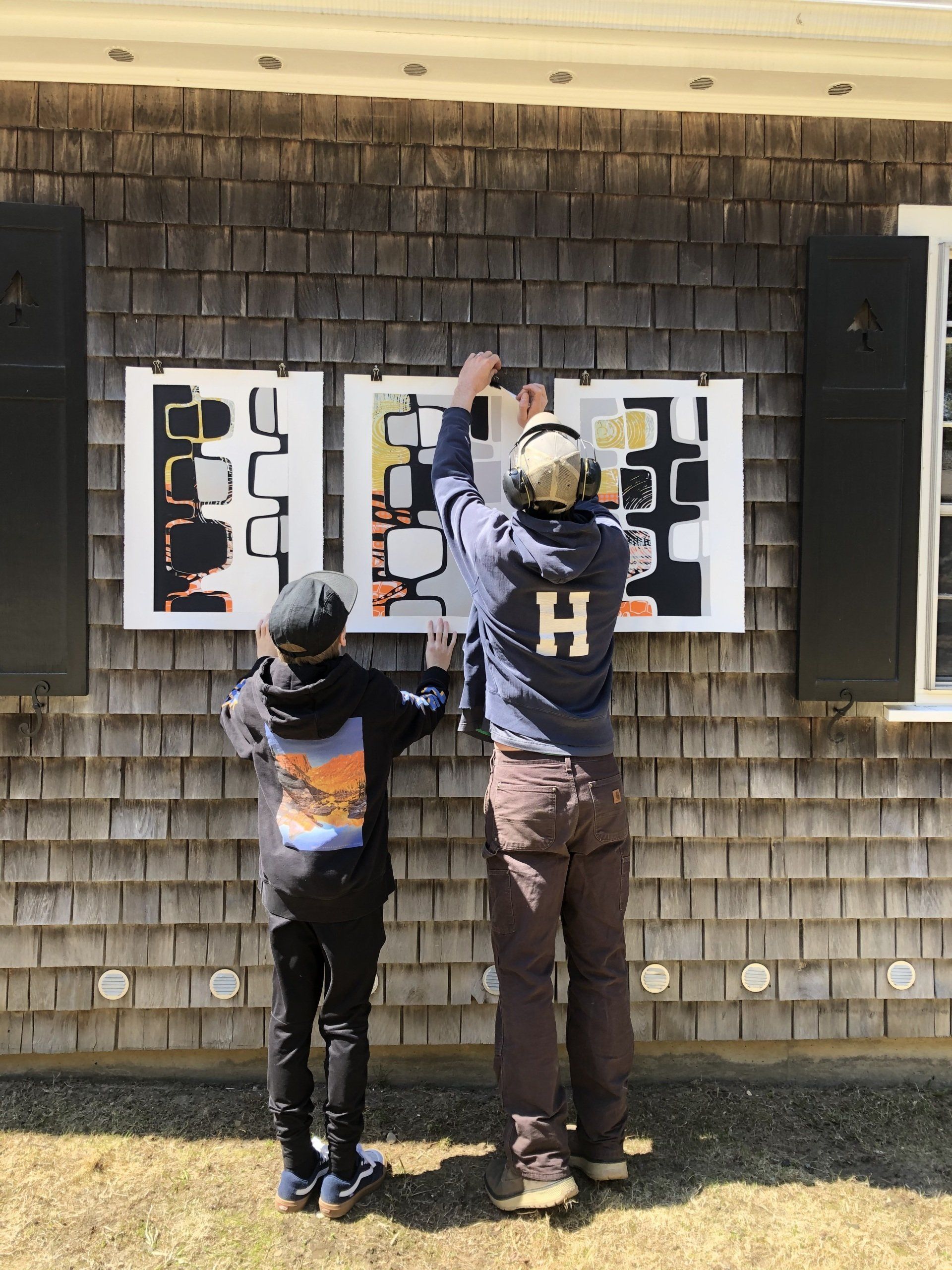 A man with the letter h on his back is standing next to a boy