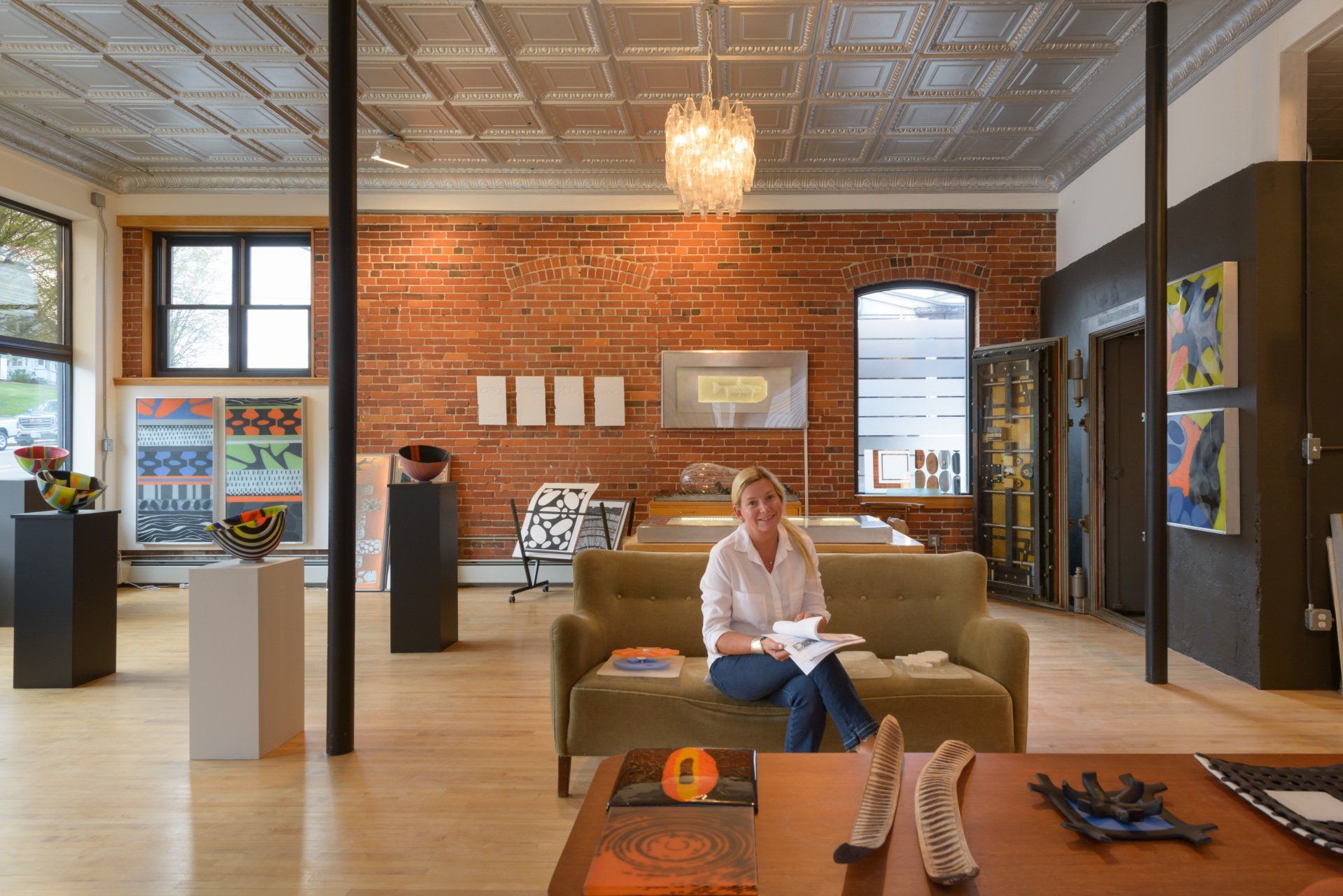 A woman sits on a couch reading a book in a living room
