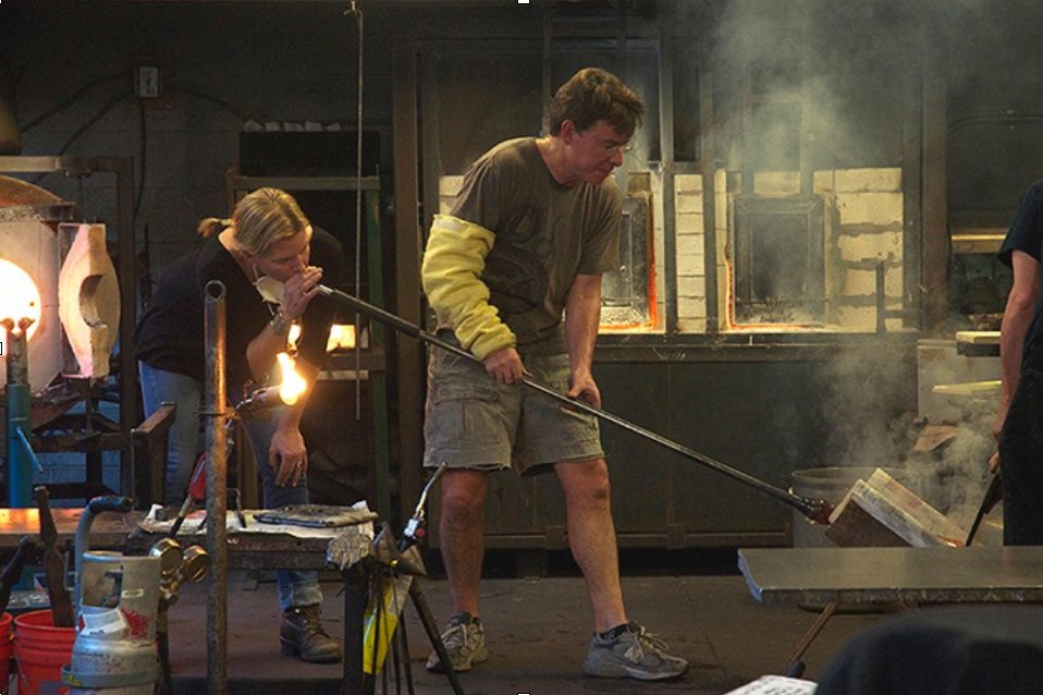 A man is blowing glass in a glass factory