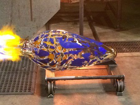 A blue and gold colored object is sitting on a cart with flames coming out of it