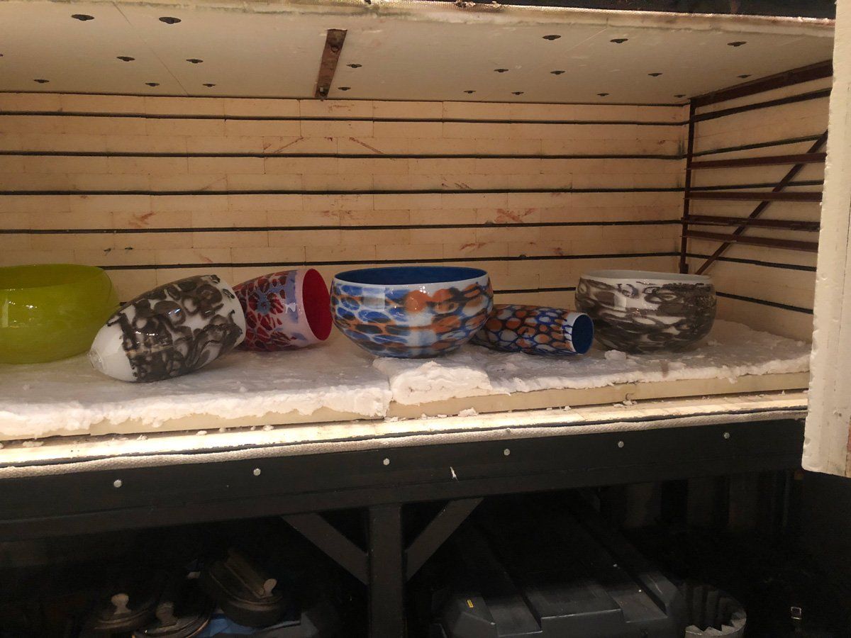 A bunch of bowls are sitting on a shelf in a room