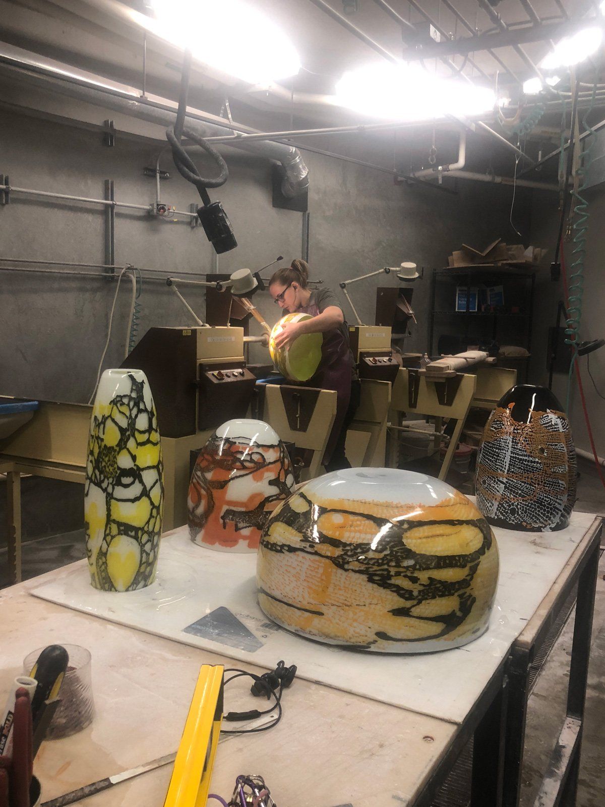 A woman is working on a vase in a workshop