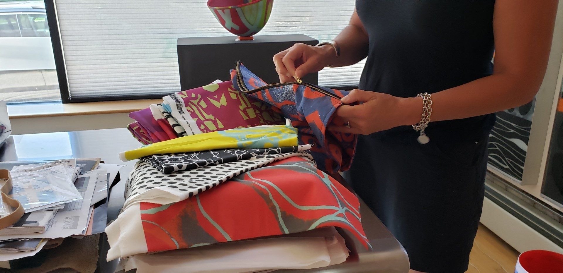 A woman is looking at a pile of colorful fabrics