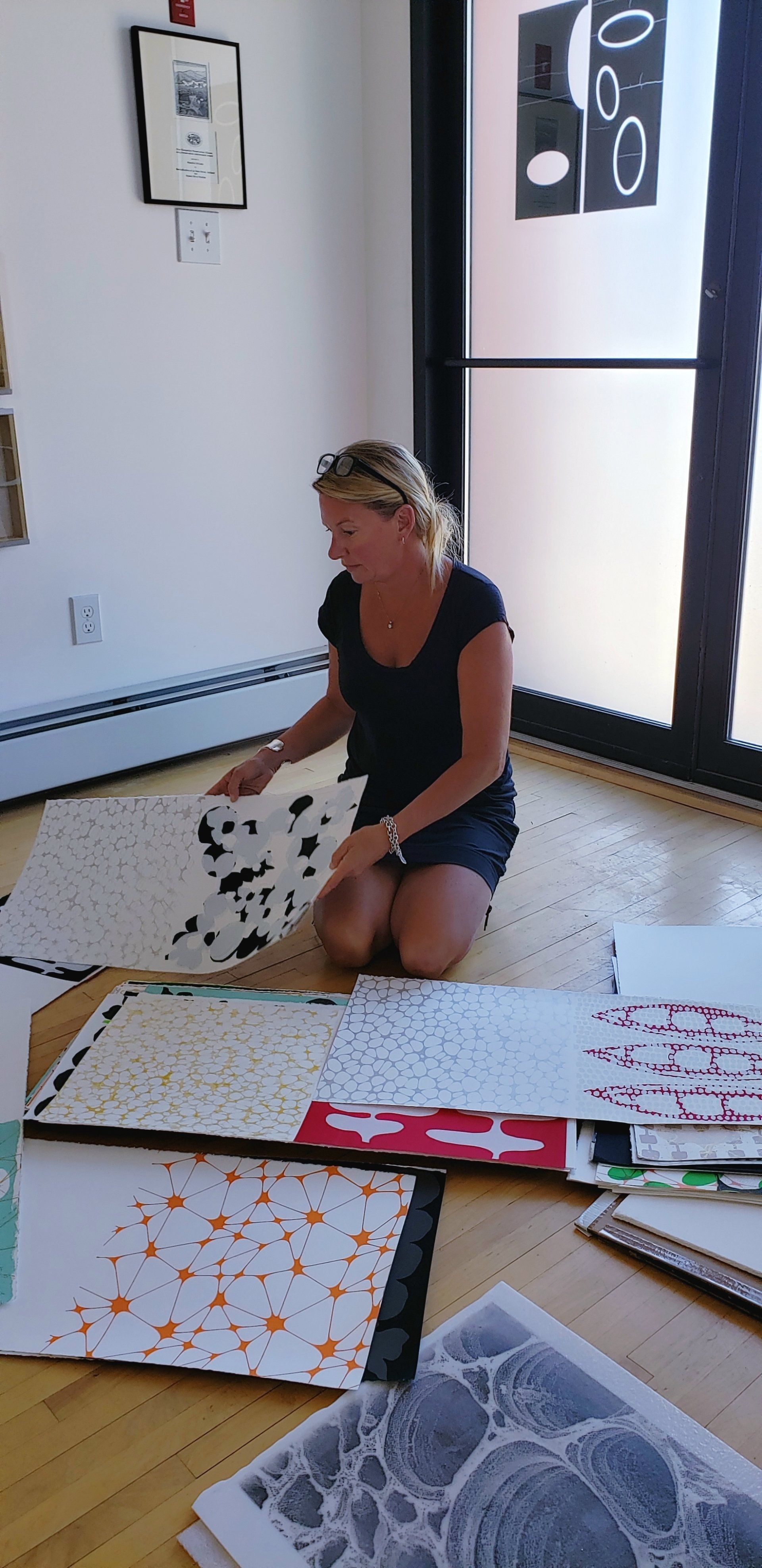 A woman is kneeling on the floor painting