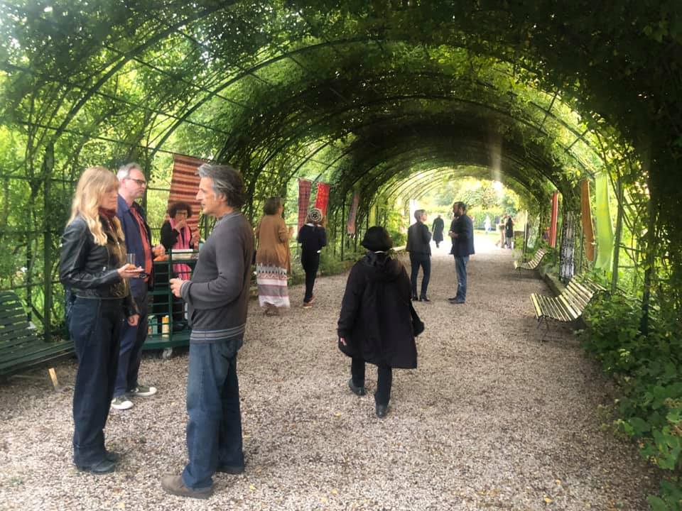A group of people are standing under a green archway