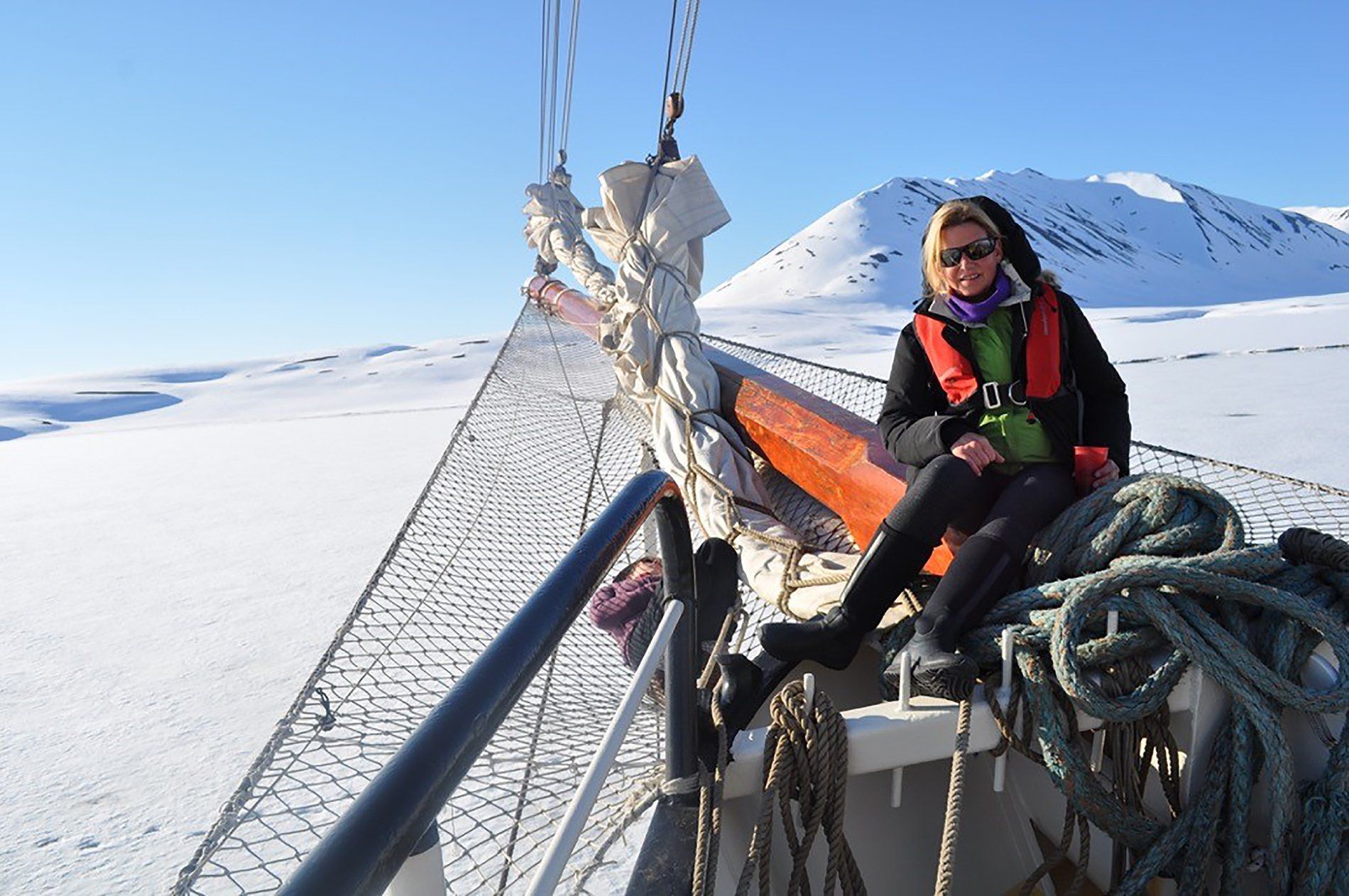 A woman is sitting on the side of a boat in the snow