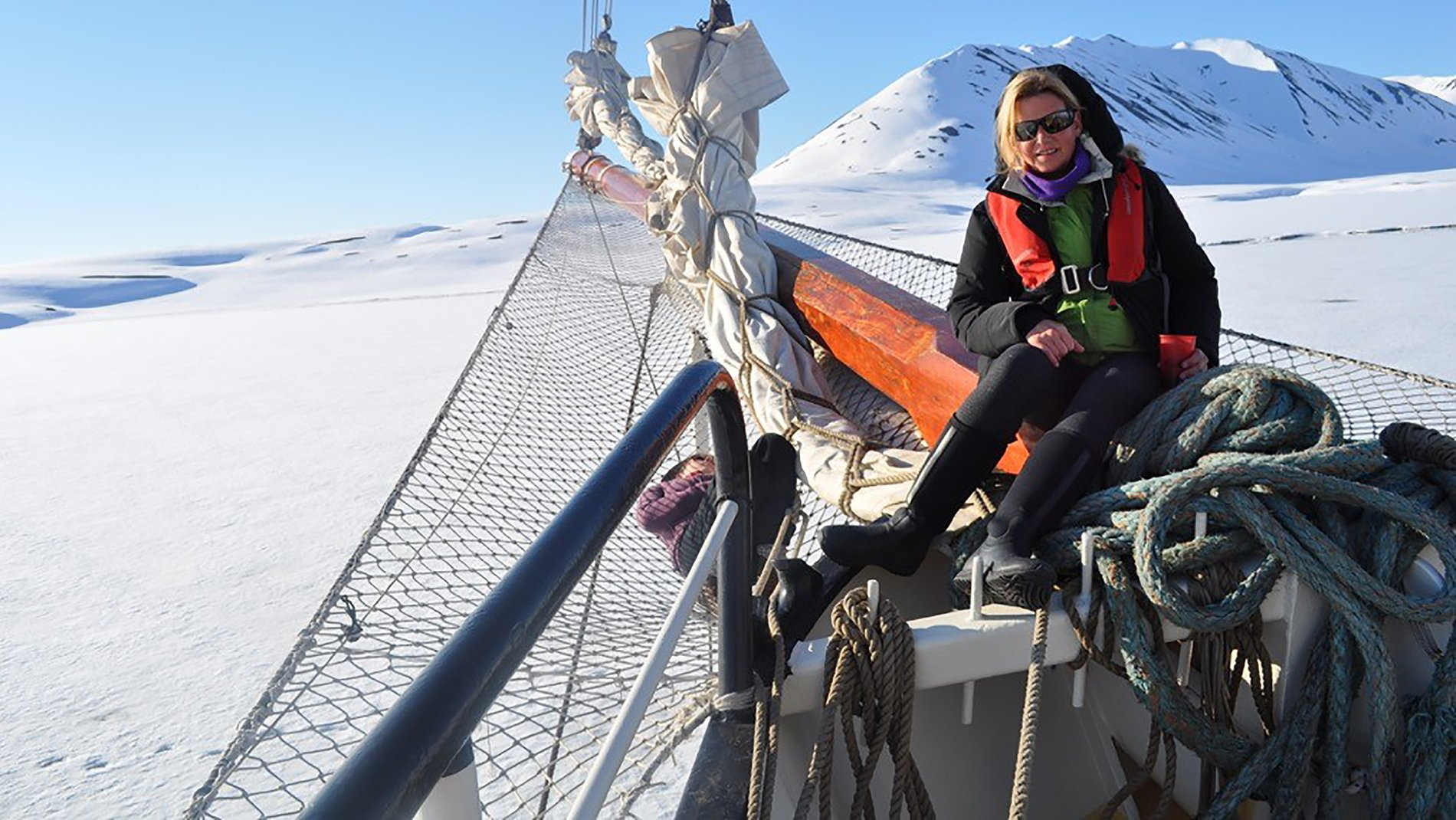 A woman sits on the side of a boat in the snow