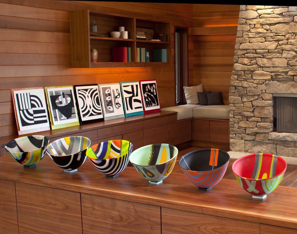 A row of colorful bowls are lined up on a wooden table