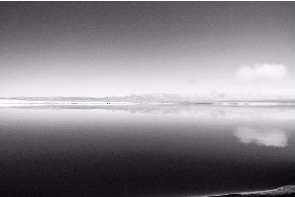A black and white photo of a body of water with clouds in the sky