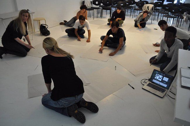 A group of people sitting on the floor with a laptop on the floor