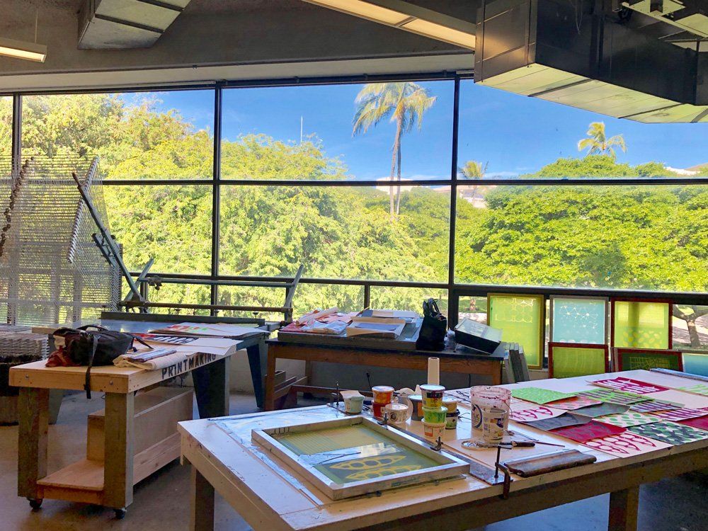 A table with paintings on it in front of a large window