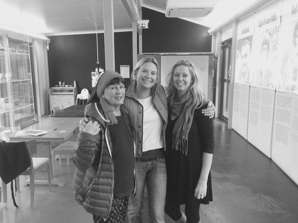 Three women are posing for a picture in a hallway.