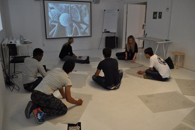 A group of people are sitting on the floor in front of a projector screen
