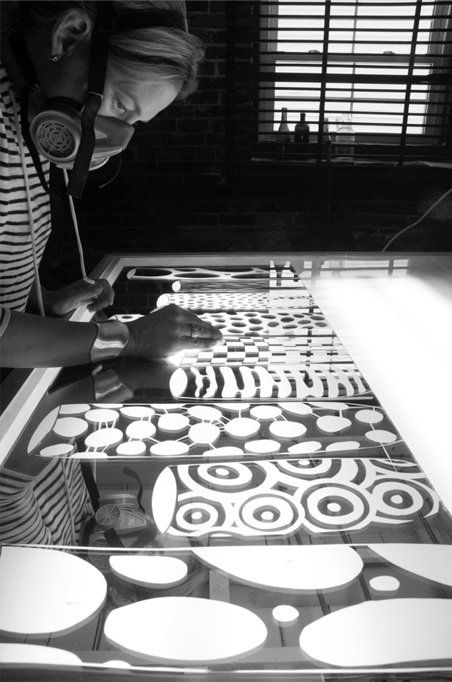 A black and white photo of a person painting a pattern on a table.